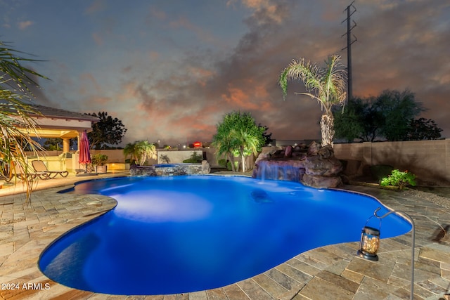 pool at dusk with a patio and pool water feature