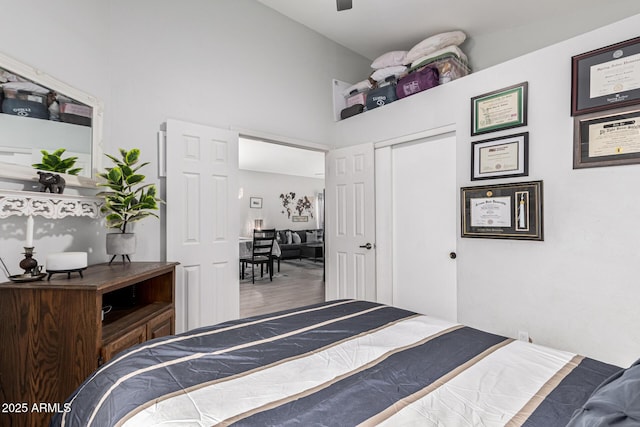 bedroom featuring high vaulted ceiling, hardwood / wood-style flooring, and a closet