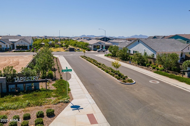 view of asphalt street featuring a residential view, sidewalks, street lighting, and curbs