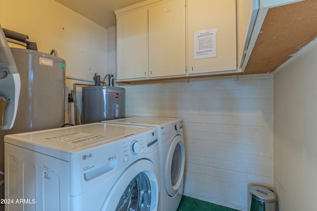 laundry area with water heater, washing machine and dryer, and cabinet space