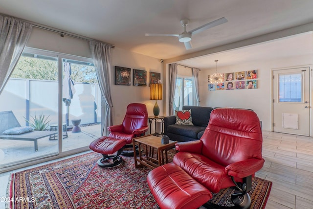 living room with ceiling fan with notable chandelier and plenty of natural light