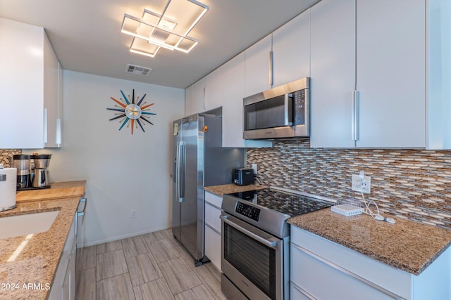 kitchen featuring visible vents, decorative backsplash, white cabinetry, and stainless steel appliances