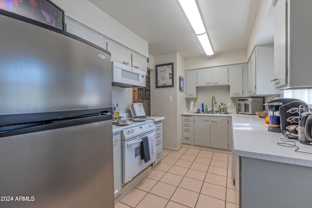 kitchen with light countertops, a sink, light tile patterned floors, and white appliances