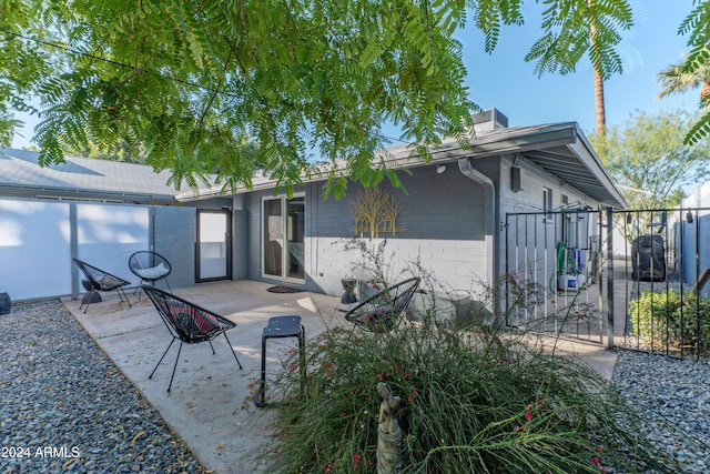 back of property featuring concrete block siding, a gate, fence, and a patio area