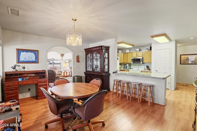 dining space featuring light wood-type flooring and an inviting chandelier