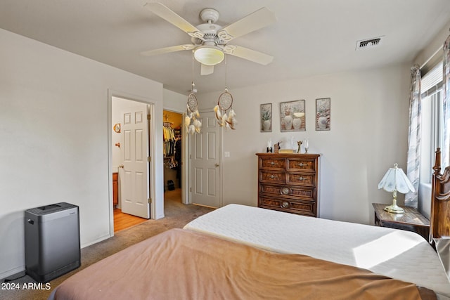 bedroom with a spacious closet, a closet, ceiling fan, and light colored carpet