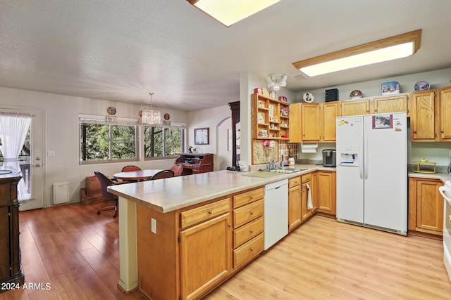 kitchen with kitchen peninsula, light hardwood / wood-style flooring, plenty of natural light, and white appliances