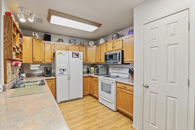 kitchen with sink, white appliances, and light hardwood / wood-style floors