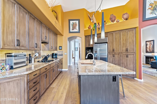 kitchen with a breakfast bar, sink, decorative backsplash, stainless steel fridge, and decorative light fixtures