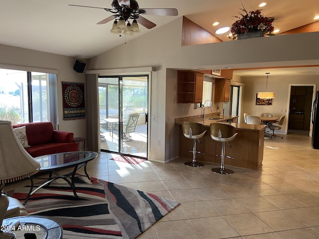 tiled living room with ceiling fan, high vaulted ceiling, a wealth of natural light, and sink