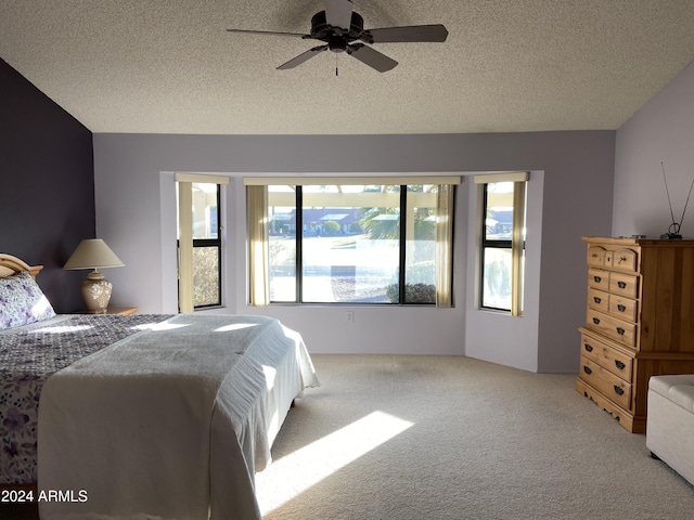 bedroom with ceiling fan, light colored carpet, and a textured ceiling