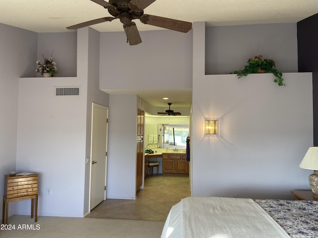 bedroom featuring light tile patterned floors, a textured ceiling, ensuite bathroom, and ceiling fan