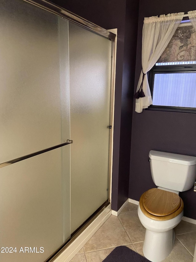 bathroom with toilet, tile patterned floors, and a shower with door