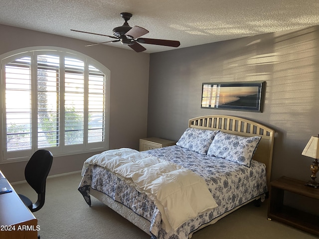 carpeted bedroom featuring ceiling fan and a textured ceiling