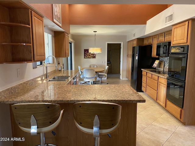 kitchen featuring a breakfast bar area, kitchen peninsula, sink, and black appliances