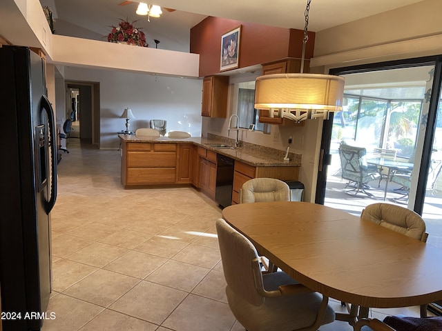 kitchen with black appliances, sink, light tile patterned floors, light stone counters, and kitchen peninsula