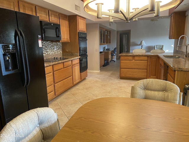 kitchen with kitchen peninsula, sink, black appliances, light tile patterned floors, and a notable chandelier