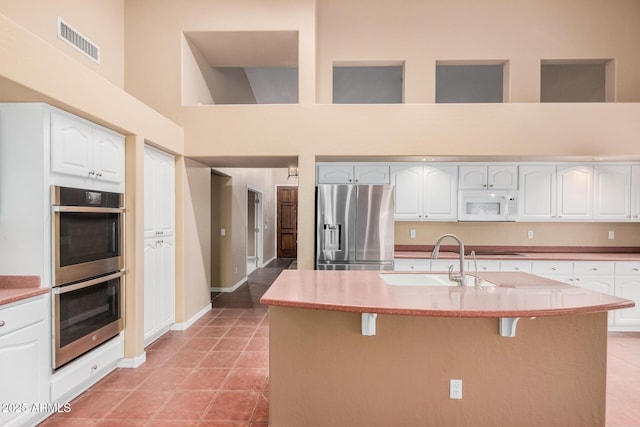 kitchen featuring white cabinetry, appliances with stainless steel finishes, a kitchen bar, and an island with sink