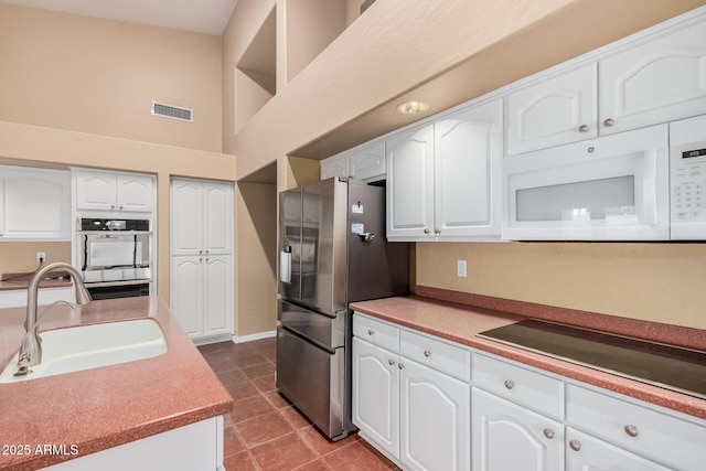 kitchen featuring stainless steel appliances, white cabinetry, sink, and tile patterned floors