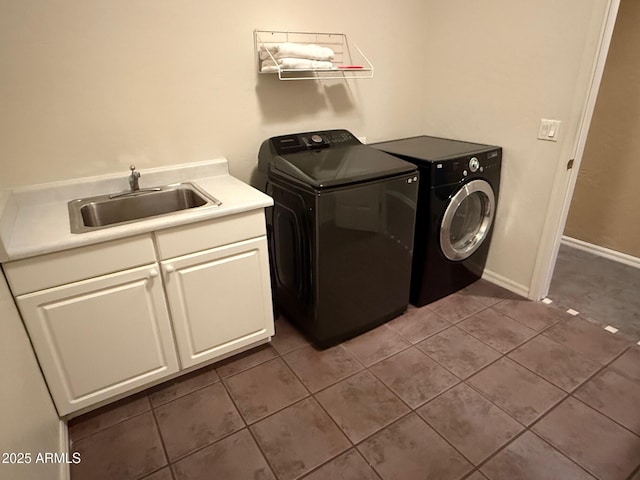 laundry area featuring sink, dark tile patterned floors, cabinets, and washing machine and clothes dryer