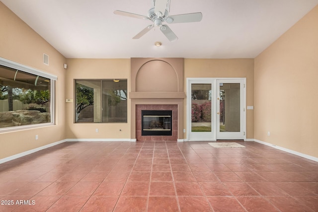 unfurnished living room with a tiled fireplace, light tile patterned flooring, and ceiling fan