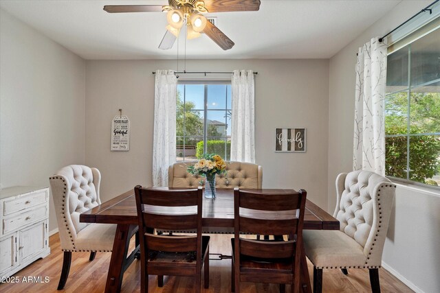 dining room featuring baseboards, light wood-type flooring, and a ceiling fan