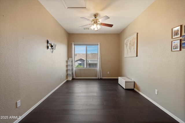 empty room featuring a ceiling fan, baseboards, dark wood finished floors, and visible vents