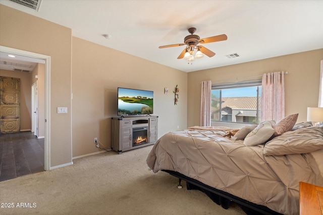 bedroom with visible vents, baseboards, carpet flooring, and a lit fireplace
