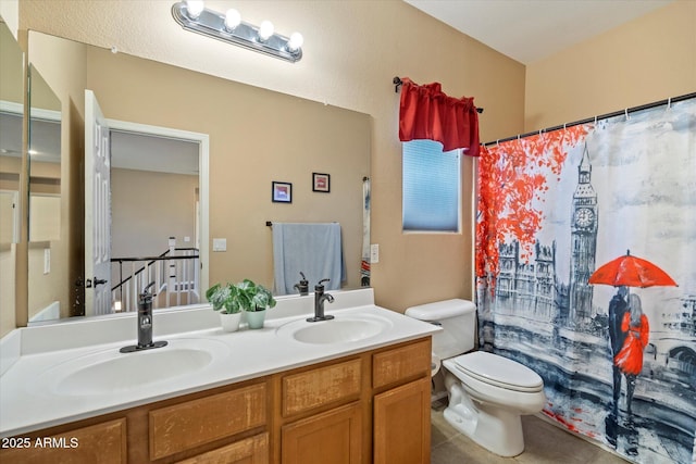 full bath featuring tile patterned flooring, double vanity, a sink, and toilet