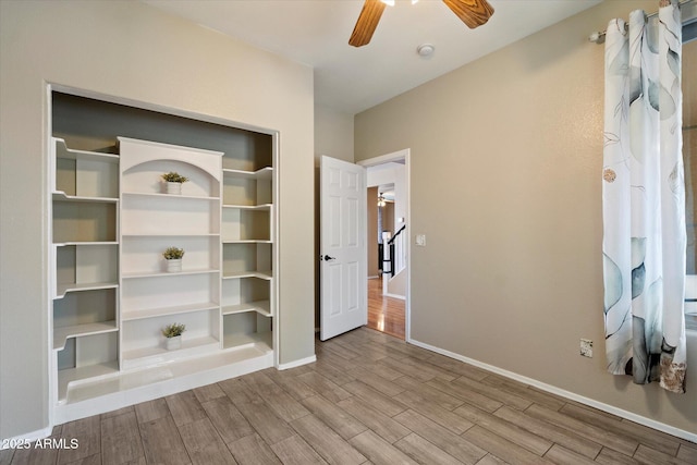 interior space featuring a closet, baseboards, a ceiling fan, and wood finished floors