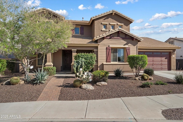 view of front of house featuring a tiled roof, an attached garage, concrete driveway, and stucco siding