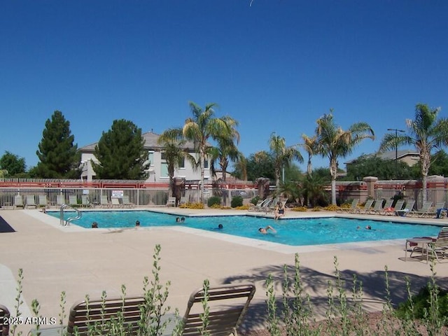 community pool with a patio area and fence