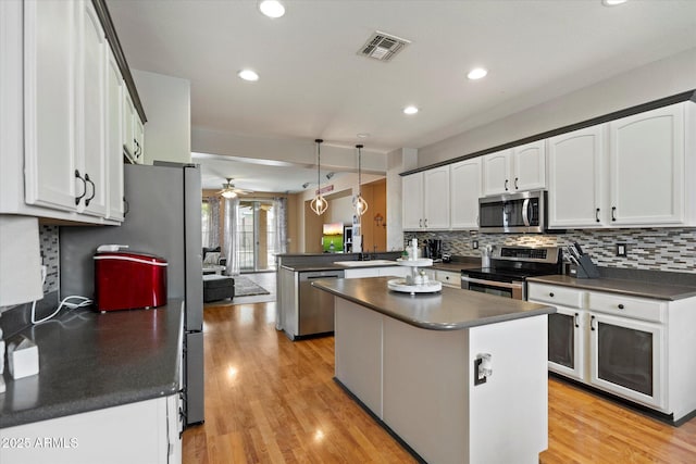 kitchen featuring a peninsula, dark countertops, visible vents, ceiling fan, and appliances with stainless steel finishes