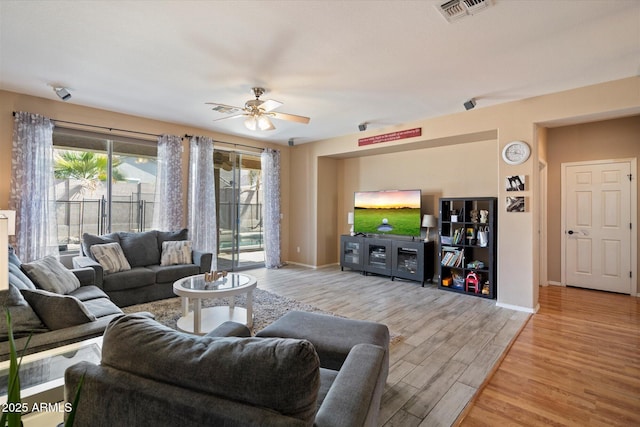 living room featuring visible vents, baseboards, a ceiling fan, and wood finished floors