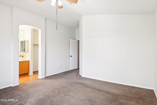 unfurnished bedroom featuring carpet floors, ensuite bathroom, vaulted ceiling, and ceiling fan