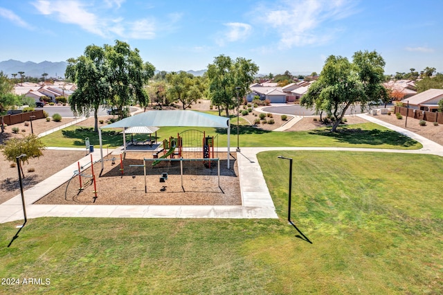 view of home's community featuring a playground, a mountain view, and a yard