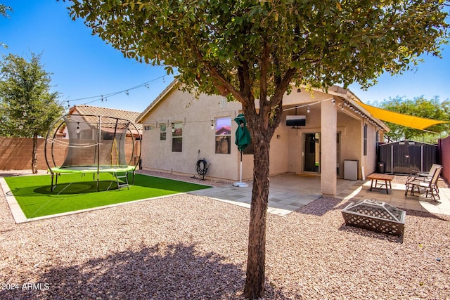 back of house featuring a patio area, a shed, a fire pit, and a trampoline