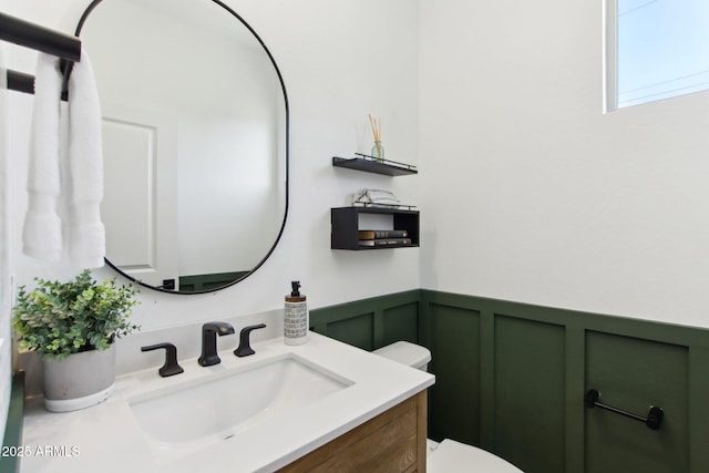 6641 N Desert Shadow Ln, Phoenix, AZ 85014 - bathroom featuring toilet, wainscoting, a decorative wall, and vanity