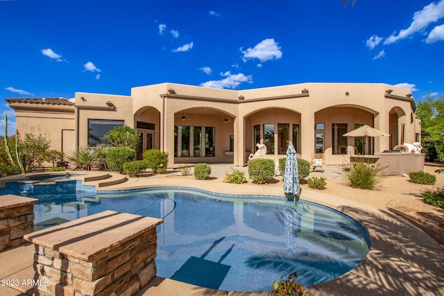 rear view of property featuring ceiling fan, a swimming pool with hot tub, and a patio area