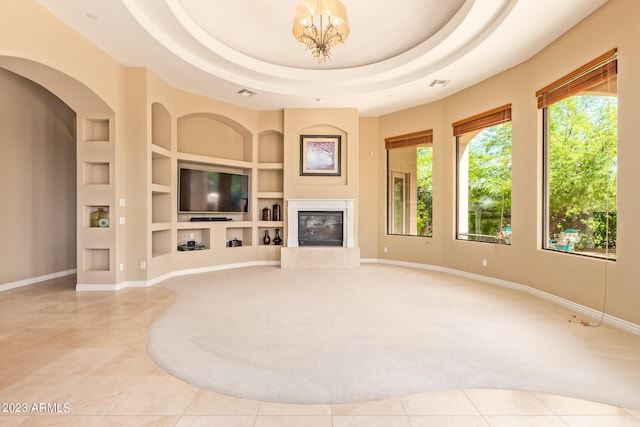 unfurnished living room featuring built in features, a notable chandelier, a tray ceiling, and light tile patterned flooring