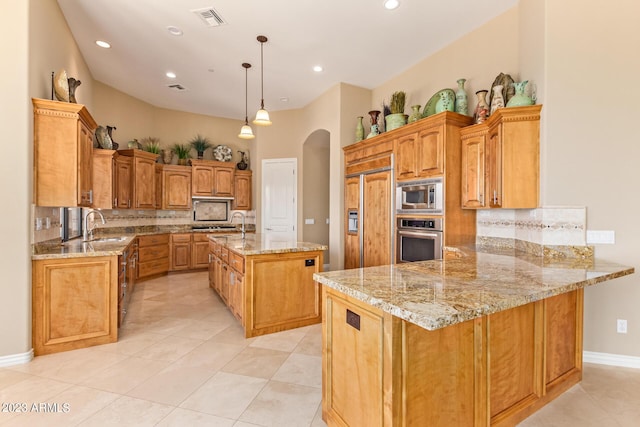 kitchen featuring decorative light fixtures, kitchen peninsula, built in appliances, and light stone countertops