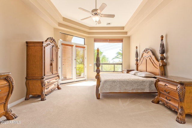 bedroom with ceiling fan, access to exterior, light colored carpet, and a tray ceiling