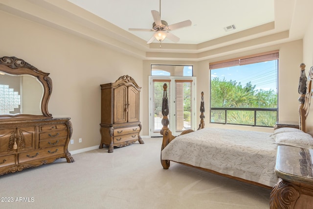 carpeted bedroom with ceiling fan, a tray ceiling, and access to outside