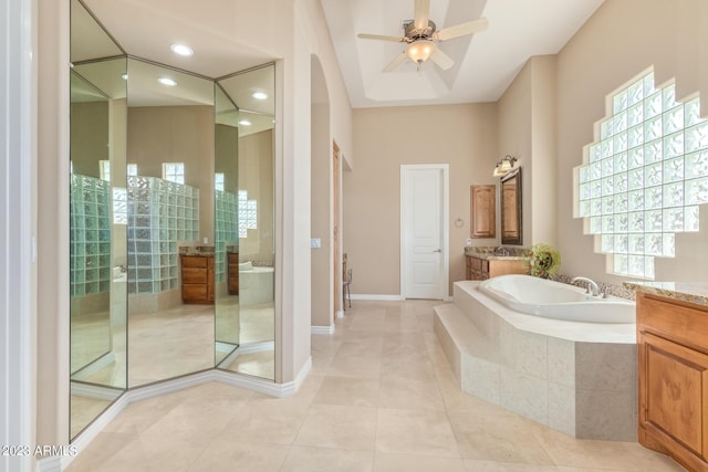 bathroom featuring tile patterned flooring, tiled tub, ceiling fan, and vanity