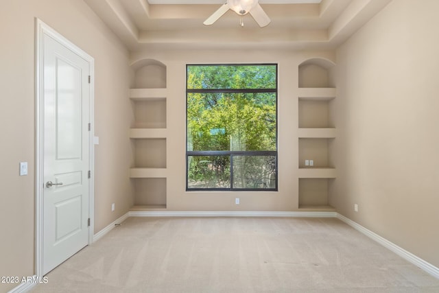 carpeted empty room featuring built in features and ceiling fan