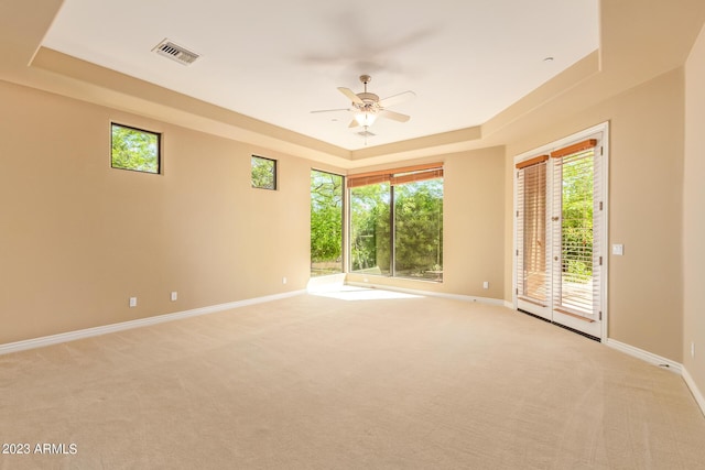 unfurnished room featuring ceiling fan, a raised ceiling, and light carpet