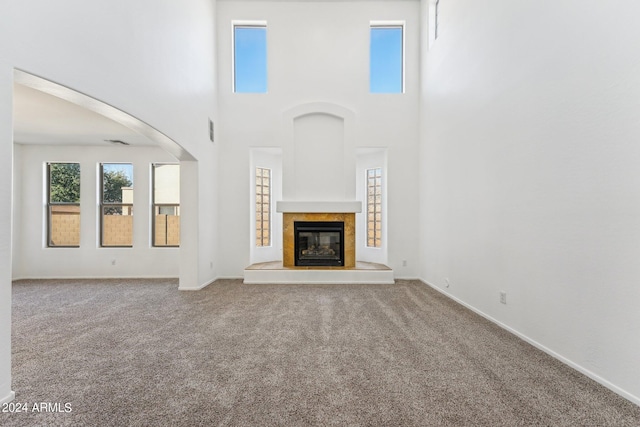 unfurnished living room with a towering ceiling and carpet