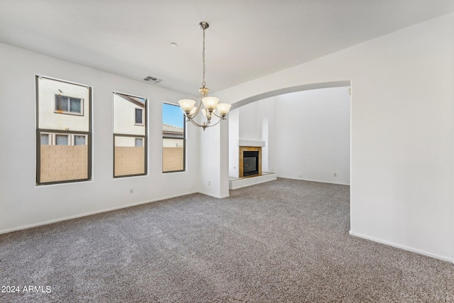 unfurnished living room featuring an inviting chandelier and carpet flooring