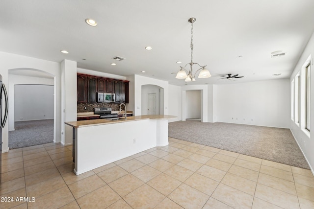 kitchen with dark brown cabinetry, appliances with stainless steel finishes, light carpet, and decorative backsplash