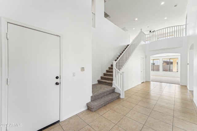 entryway with a high ceiling, light tile patterned floors, and ceiling fan